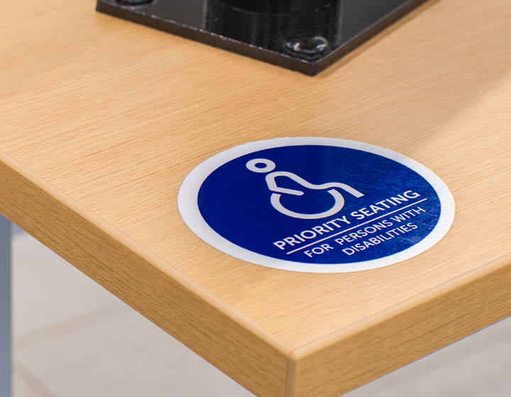 An image of the corner of a table with a sticker that says Priority Seating for Persons with Disabilities.