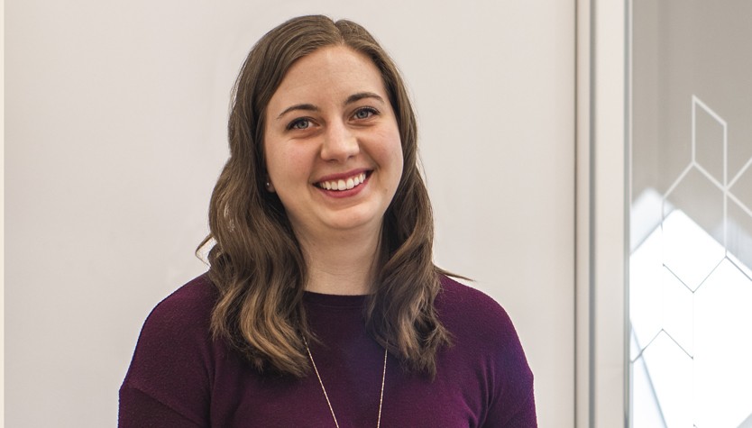 Megan Powell smiling and standing in front of a meeting room with glass doors.