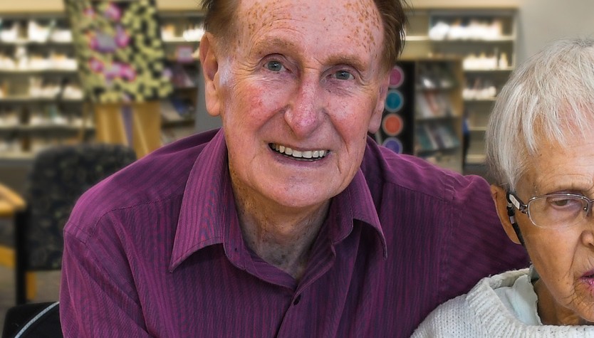 Frank OKeeffe and an elderly woman sitting at a table in a library.