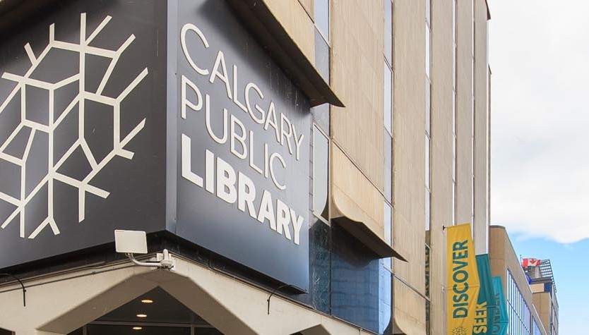 Photograph of the exterior of a building with a large grey sign that reads "Calgary Public Library."