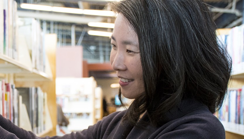 Teresa Wong selecting a book from a shelf in a library.