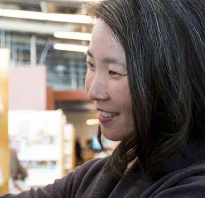 Teresa Wong selecting a book from a shelf in a library.