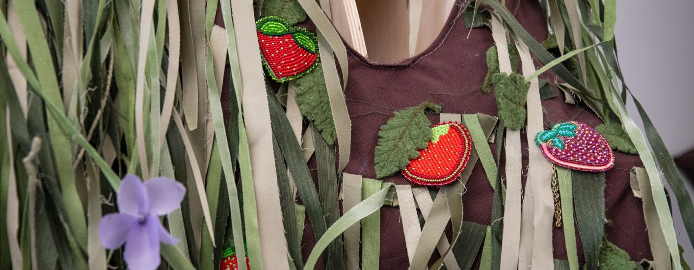 Beaded strawberries on brown cloth with green strips of fabric.