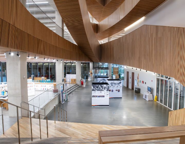 background image: A photograph shows a wide-open space with a display set up. On the left side, there are visuals of bookshelves and wood paneling showing the different floors.