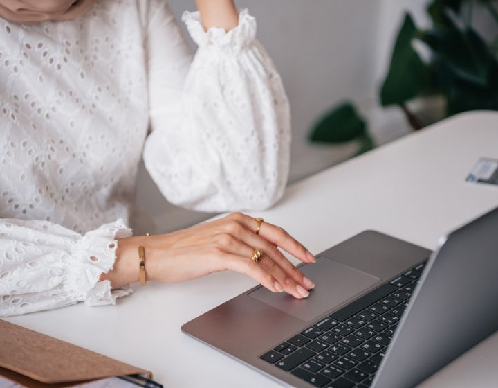 background image: A woman in a white blouse sitting at a desk using a laptop.