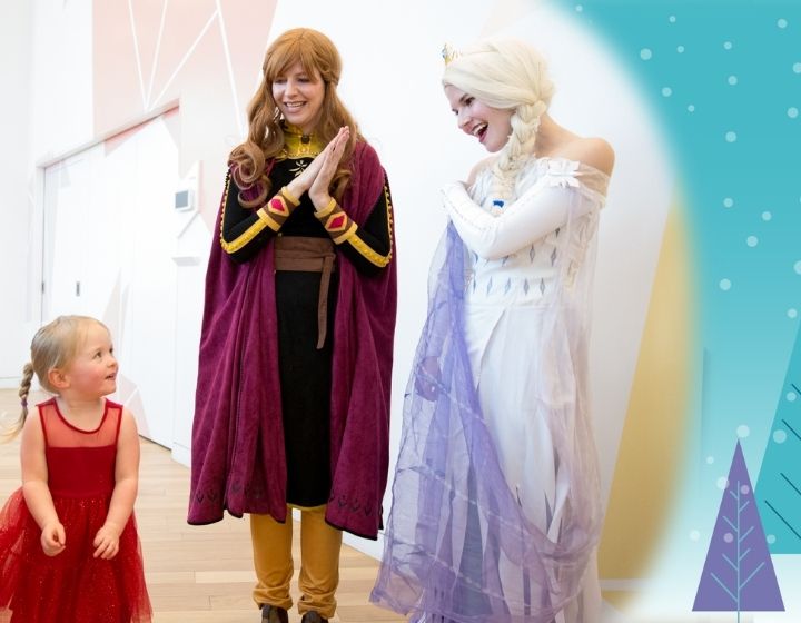 background image: A little girl in a red dress looking up at Anna and Elsa from Frozen. On the right side there is an illustration of a purple and blue tree.